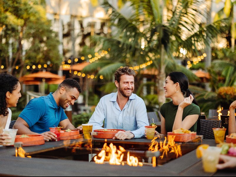 a photo of couples laughing over a firepit